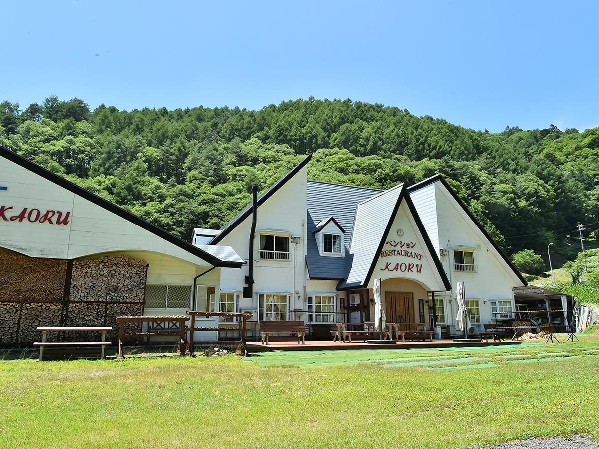 新緑の山を背にしたペンションかおるとテラス