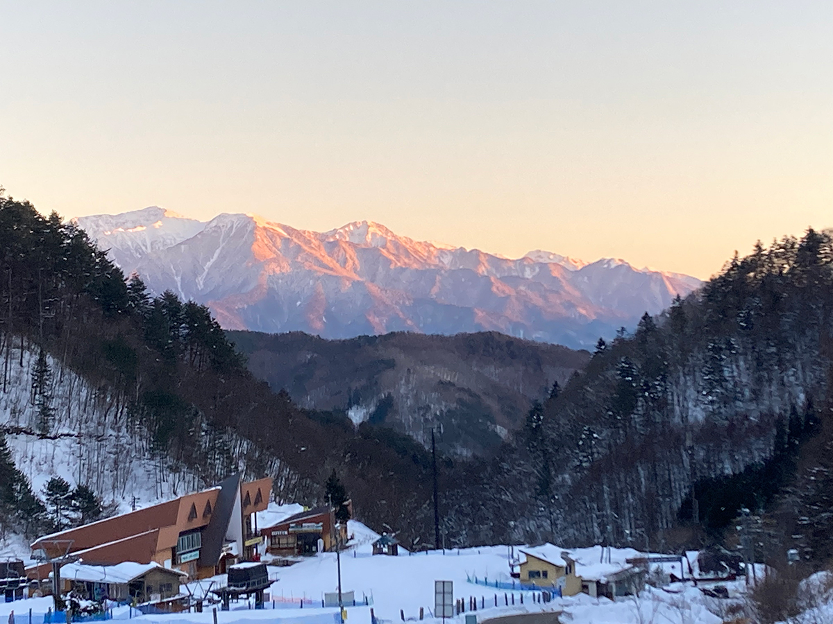 朝日に染まる雪山と麓のスキー場