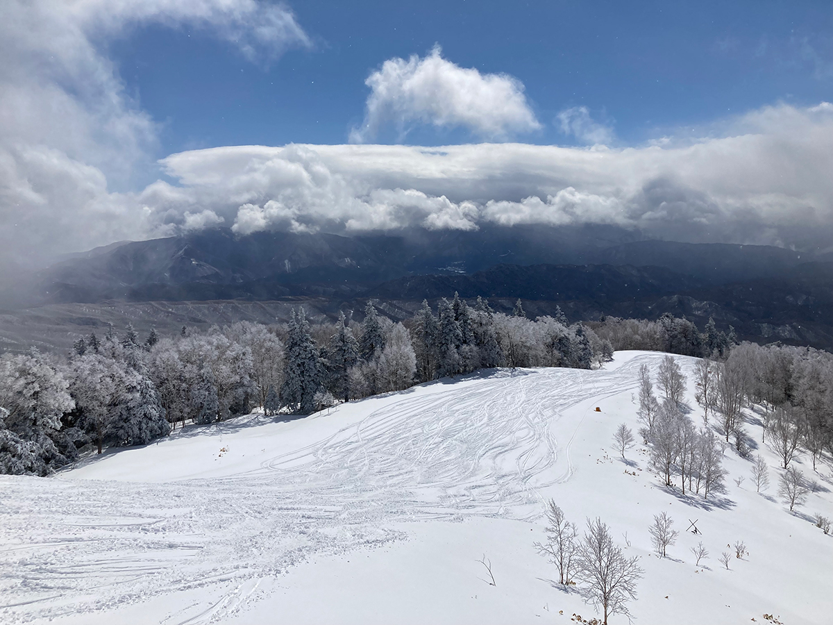 山頂付近から望む雪原と雲の広がる山並み