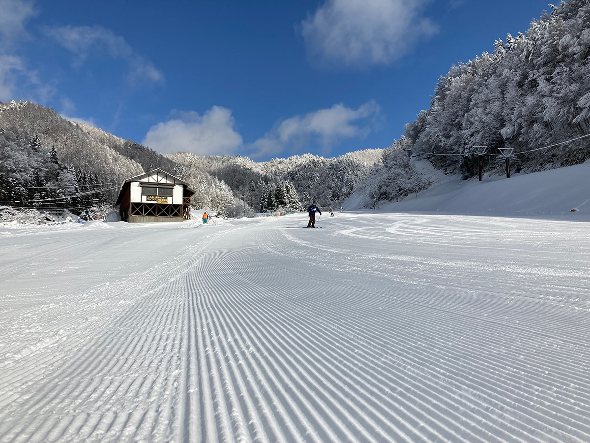 圧雪されたばかりのゲレンデと雪化粧した山