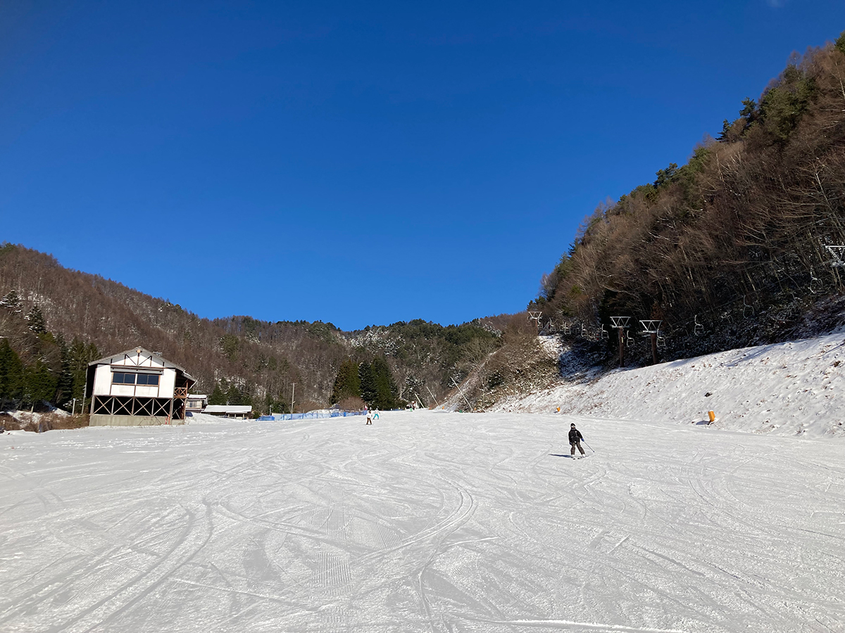青空の下、広々としたゲレンデを滑るスキーヤー